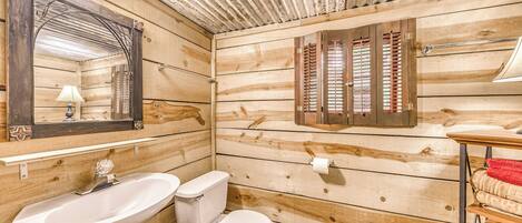 A wooden cabin bathroom with a sink, toilet, and mirror.