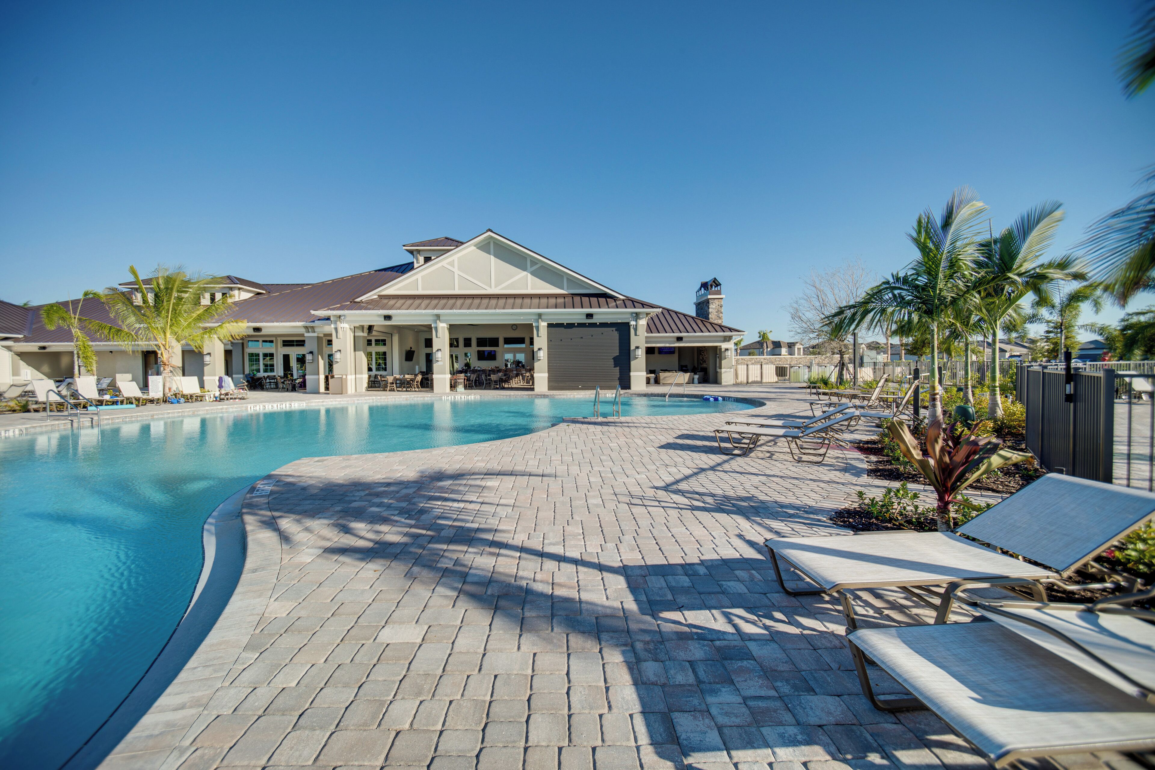 A swimming pool with lounge chairs and a covered patio area.