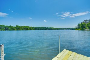 A wooden dock extending into a calm lake with a forested shoreline. - 'wet Feet Retreat' Year-round Cabin in Frederic (Frederic)