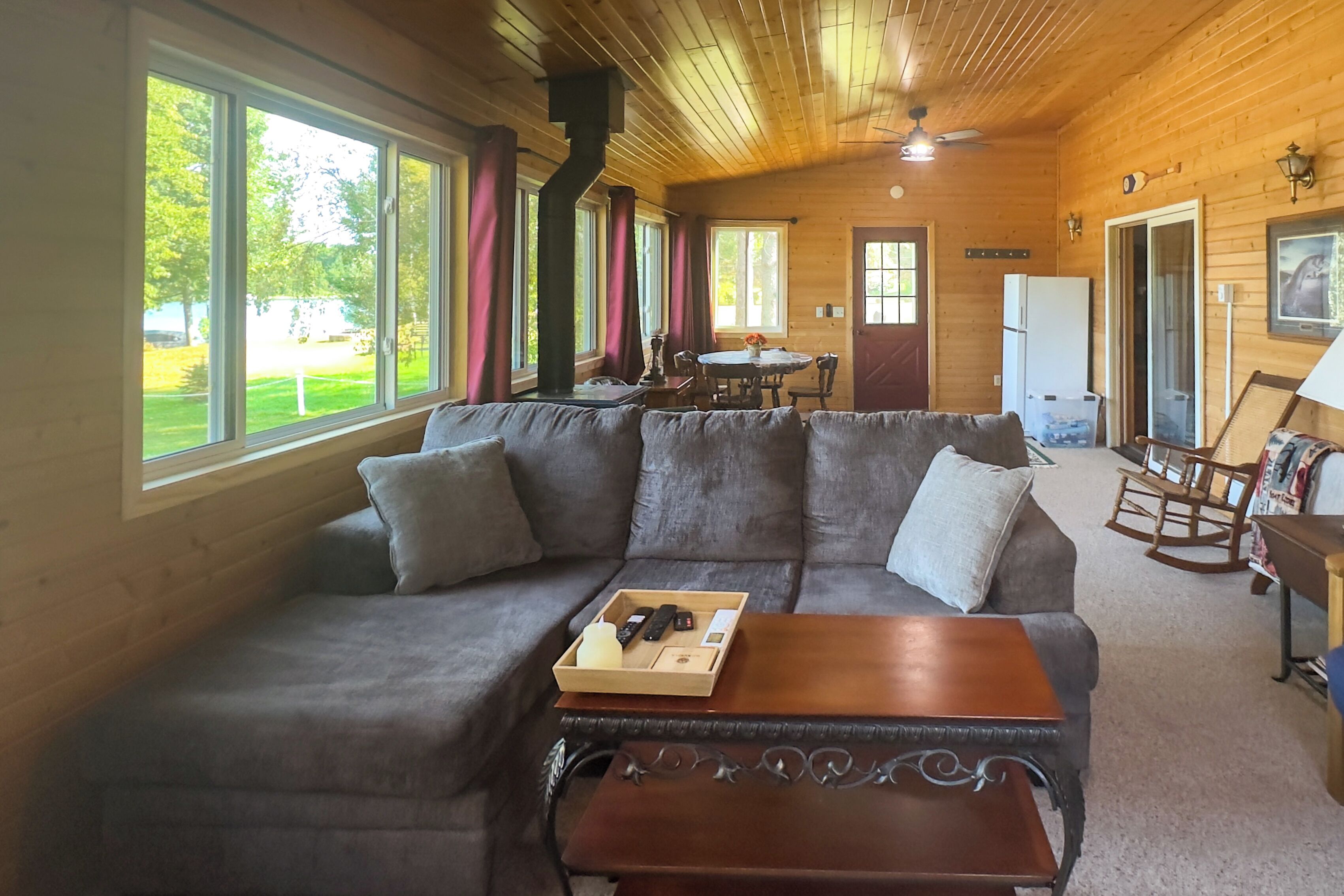 A cozy cabin interior with a sofa, a wooden table, and a dining area.