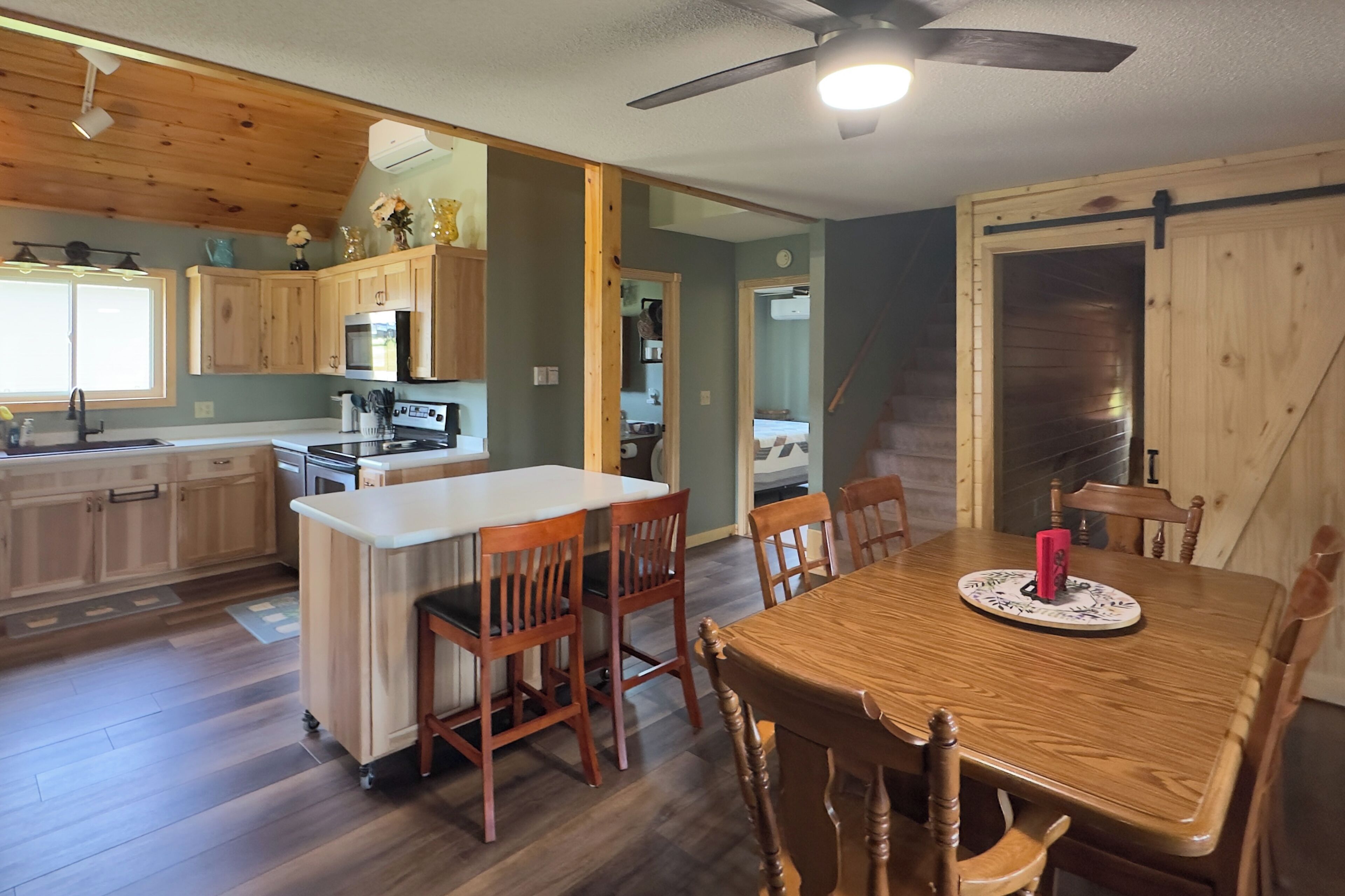 A kitchen with wooden cabinets, a central island, and a dining area with a table and chairs.
