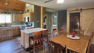 A kitchen with wooden cabinets, a central island, and a dining area with a table and chairs.