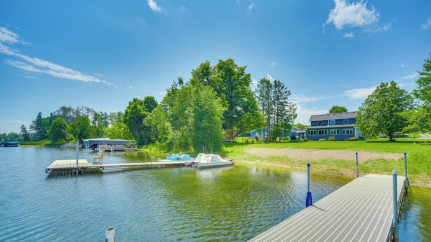 A lakeside dock with a boat, a wooden pier, and a house in the background. - 'wet Feet Retreat' Year-round Cabin in Frederic (Frederic)