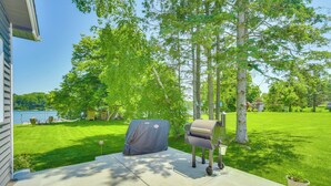 A backyard with a grill, a covered barbecue, a hammock, and a view of a lake. - 'wet Feet Retreat' Year-round Cabin in Frederic (Frederic)