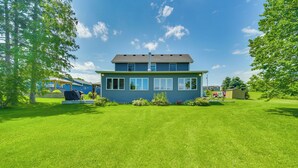 A two-story house with a blue exterior and a well-maintained lawn in front. - 'wet Feet Retreat' Year-round Cabin in Frederic (Frederic)