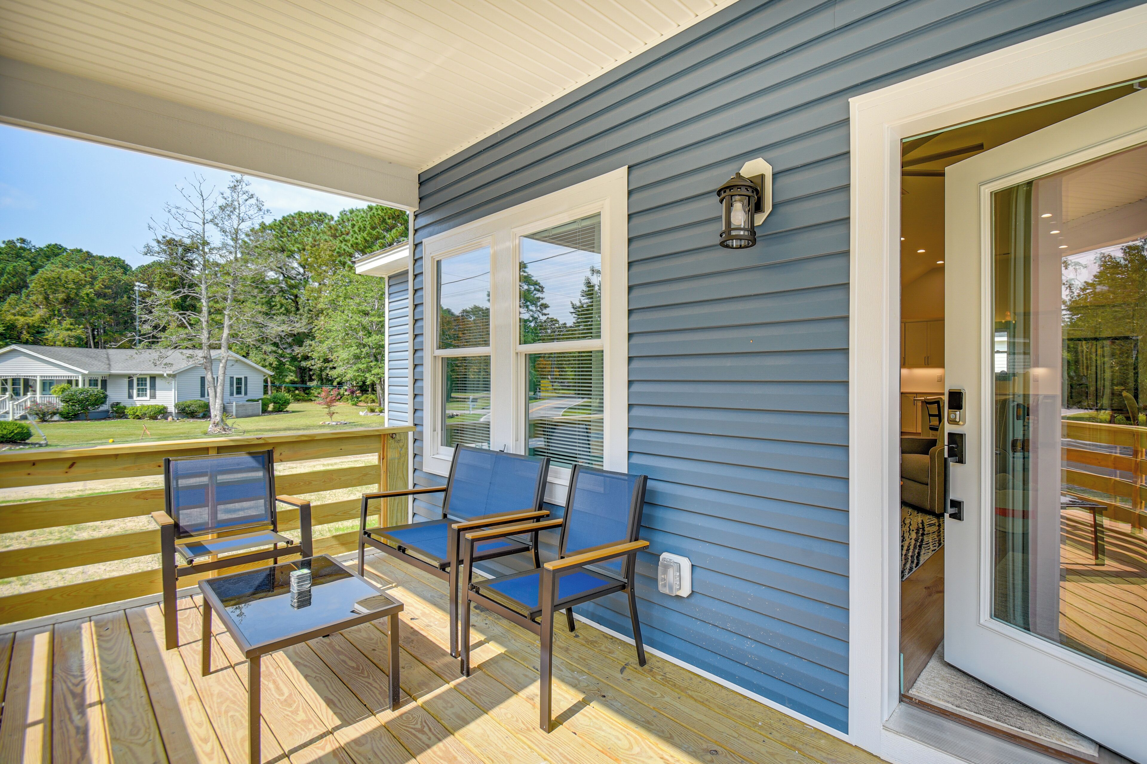 A covered deck with outdoor seating and a glass door leading to an interior space.