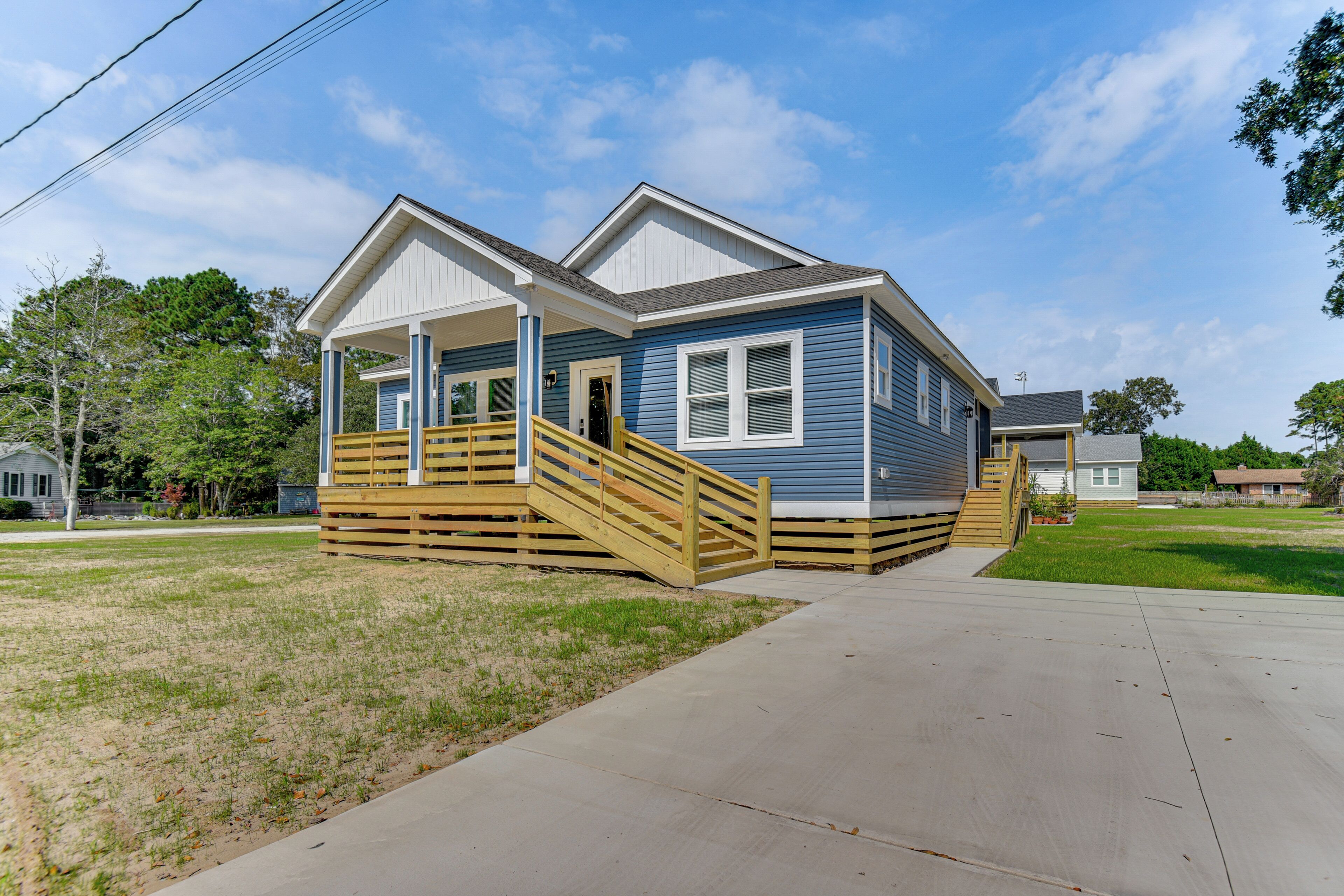 A two-story house with a front porch, a wooden staircase, and a driveway.