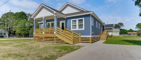 A two-story house with a front porch, a wooden staircase, and a driveway.
