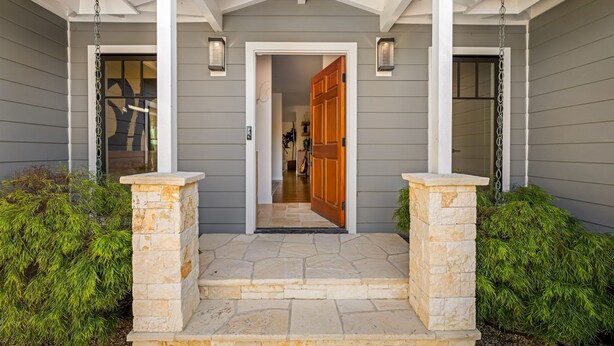 A house entrance with a stone staircase, a wooden door, and two wall-mounted lights.