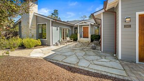 A modern house with a stone patio, a wooden door, and a mailbox.