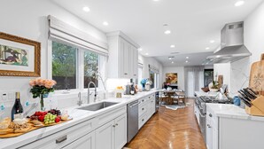A modern kitchen with white cabinetry, a wooden countertop, and a central island.