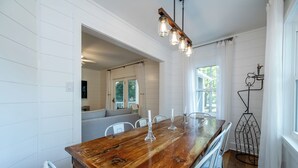 A dining area with a wooden table, white chairs, and a chandelier.
