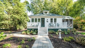 A house with a front porch, a small entryway, and a garden with mulch and plants.