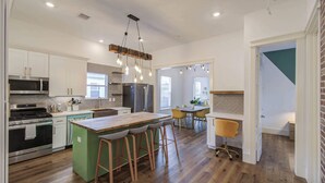 A modern kitchen with a central island, stainless steel appliances, and pendant lighting.