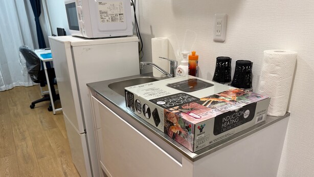 A kitchen area with a microwave, a sink, and a box of induction heating cookware. - Y202 - Great Quiet Location Yoga (Setagaya City)
