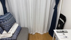 A room with a bed, a bedside table with a remote control, and a window with curtains. - Y202 - Great Quiet Location Yoga (Setagaya City)
