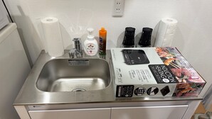 A stainless steel sink with a paper towel holder, a soap dispenser, and a box of induction cookware. - Y202 - Great Quiet Location Yoga (Setagaya City)