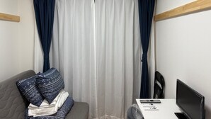 A room with a grey sofa, a TV, and a window with white and dark blue curtains. - Y202 - Great Quiet Location Yoga (Setagaya City)