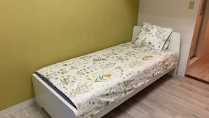 A small, single-bed room with a floral-patterned bedspread and a plain white headboard.