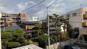 Zona residencial com edifícios modernos e tradicionais, um carro estacionado na rua e céu claro.