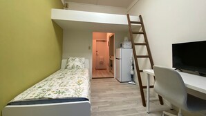A small, compact room with a bunk bed, a desk with a chair, a television, and a refrigerator. - Y303 - Sunshine Yoga (Setagaya City)
