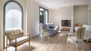 Un salon spacieux doté d’une grande fenêtre, d’une cheminée et d’un coin salon confortable.