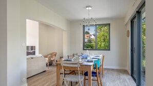 Un coin repas avec une table et des chaises en bois, un lustre et une fenêtre donnant sur un paysage verdoyant.