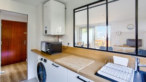 A compact kitchen with a washing machine, a microwave, and a large window. - 130m from the beach, nice flat for 4 (Pléneuf-Val-André)