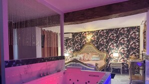 A luxurious room with a large bed, a modern jacuzzi, and a floral wallpaper.