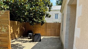A small outdoor patio area with a wooden fence, two wicker chairs, and a small table.