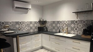 A modern kitchen with a black countertop, white cabinets, and patterned backsplash.