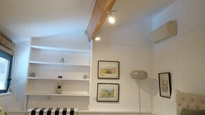 A room with white walls, a black and white striped bench, and two framed pictures on the wall.
