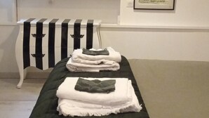 A room with a massage table, a striped table, and two framed artworks on the wall.