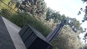 A rooftop terrace with a pergola, seating area, and a view of surrounding trees.