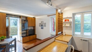 A modern kitchen with wooden cabinets, a built-in oven, and a dining area with a bench. - Ca da Lalla by Wonderful Italy (Varazze)
