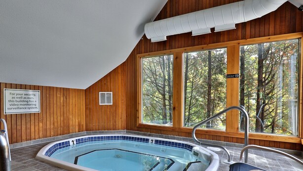 Una stanza con pannelli in legno, piscina, ampie finestre e un cartello sulla sicurezza.