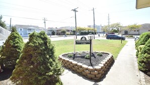 Schild für das Virginian Condominium 1101, umgeben von einer angelegten Grünfläche mit geschnittenen Büschen und einem gepflasterten Weg.