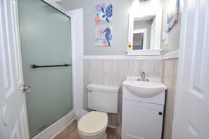 Un baño con inodoro, lavabo y ducha. Hay azulejos decorativos en la pared y un espejo sobre el lavabo.