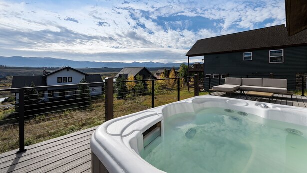 A hot tub on a wooden deck with a view of houses and mountains in the background. - Scenic Perch 2 Bedroom Home (Tabernash)