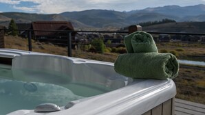A hot tub with a wooden deck and a view of mountains and a small town in the background. - Scenic Perch 2 Bedroom Home (Tabernash)
