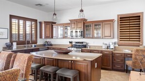 A spacious kitchen with a large island, wooden cabinets, and a stainless steel oven. - 4BR Heated Pool Estrella Mountain House (Goodyear)