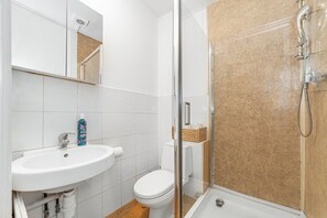 A bathroom with a white sink, toilet, and shower. - Chic One Bed City Flat (London)