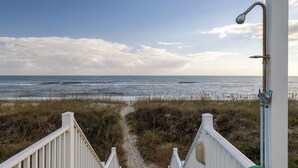 Ein Weg führt zu einem Strand mit Blick auf das Meer und einer Straßenlaterne.