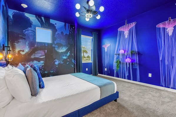 A bedroom with a bed, a ceiling fan, and a mural of a forest scene.