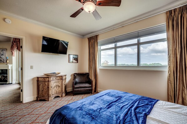 A bedroom with a bed, a television, a chair, a window with curtains, and a ceiling fan. - ✨Water Views | Great Amenities | AAA Four Diamond Resort | The Marina 4-604B✨ (Myrtle Beach)