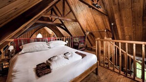A cozy attic bedroom with a wooden ceiling, a bed with white linens, and a plaid blanket. - The Tabernacle, Design-led Converted Chapel with Hot Tub, Highland Perthshire (Aberfeldy)