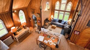 A cozy cabin with wooden walls and a loft bedroom with a large window. - The Tabernacle, Design-led Converted Chapel with Hot Tub, Highland Perthshire (Aberfeldy)