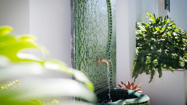 Uma fonte com bico e parede revestida de azulejos.
