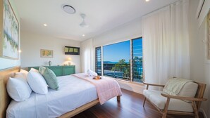 Quarto com cama, cadeira, varanda e vista, e um armário verde.