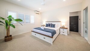Un dormitorio con cama, mesitas de noche, planta en maceta y armario.